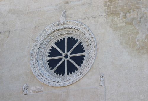 Free A beautifully carved rosette window set in a historic stone wall façade. Stock Photo