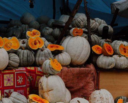 A vibrant display of white and orange pumpkins, freshly sliced and arranged in a market setting.
