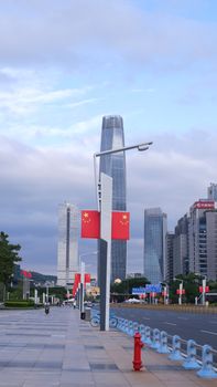 Skyline with modern skyscrapers and Chinese flags lining an empty urban street.