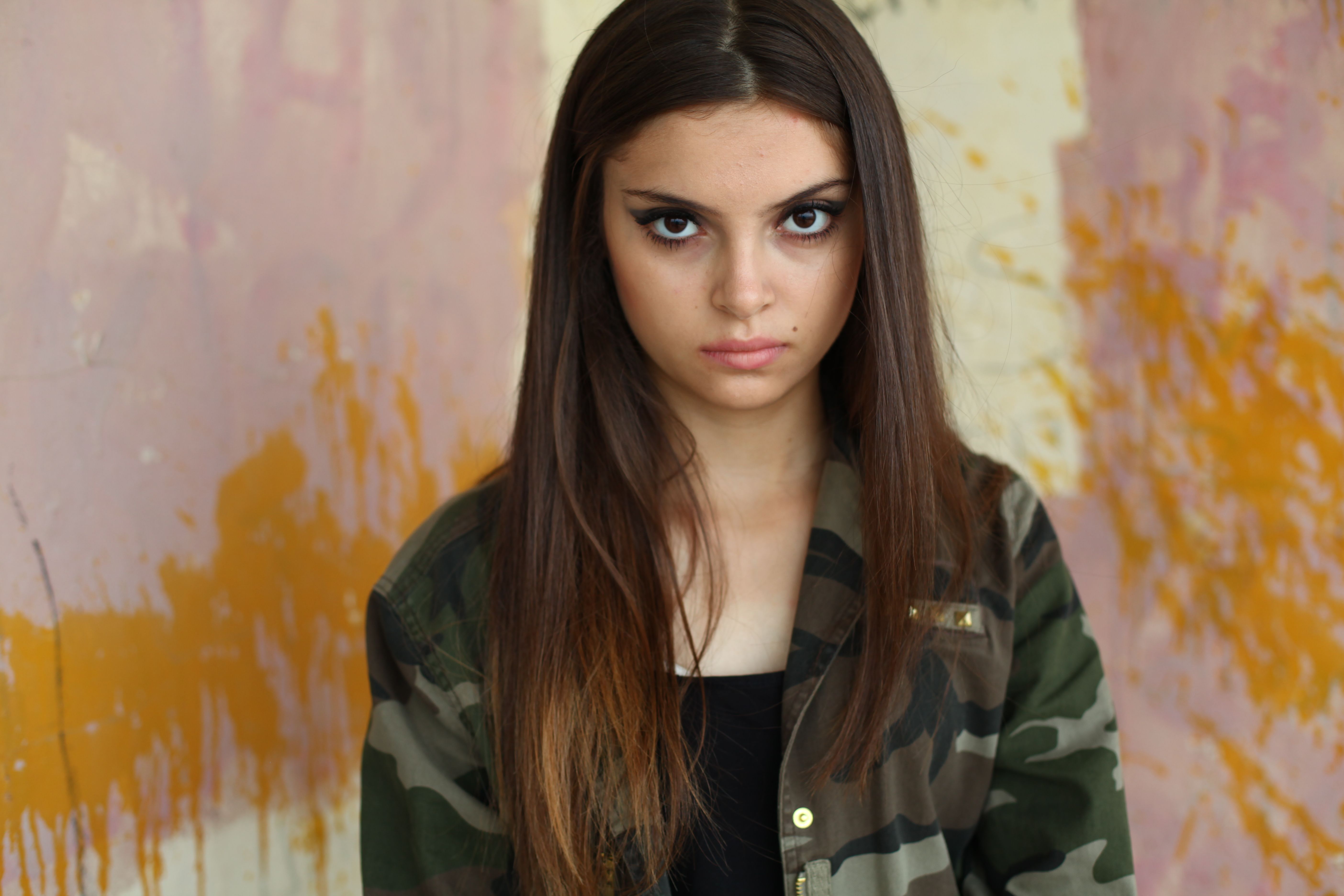 Young Woman in Camouflage Top Against Artistic Wall · Free Stock Photo