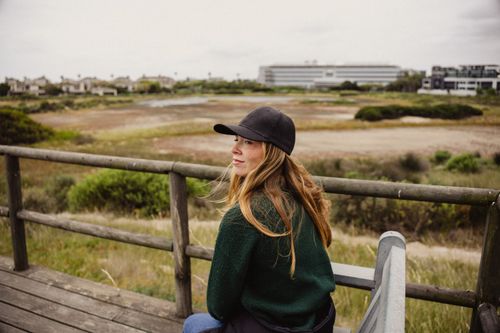 Free A young woman in casual wear relaxes outdoors, enjoying the scenic view. Stock Photo