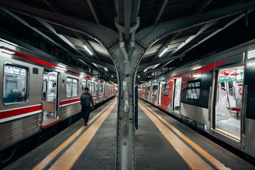 Free A bustling urban train station with trains on both sides and a few passengers on the platform. Stock Photo