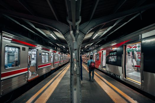 Traveler with backpack walks through a vibrant urban train station, capturing the essence of city life.