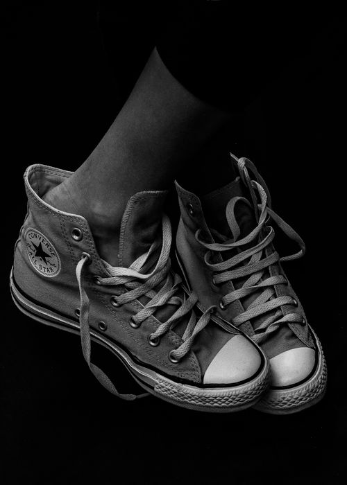 Free Artistic black and white photo of classic canvas sneakers on a dark background. Stock Photo