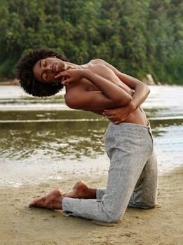 A man gracefully poses in yoga by a riverside beach, showcasing flexibility and tranquility.