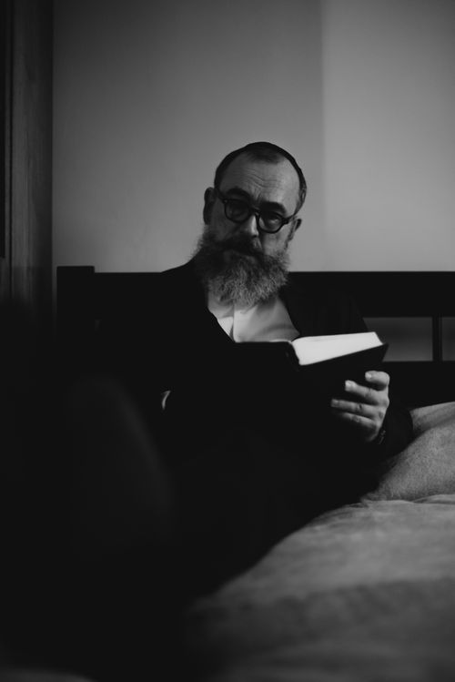 Free Monochrome image of a bearded man reading a book in a quiet, contemplative setting. Stock Photo