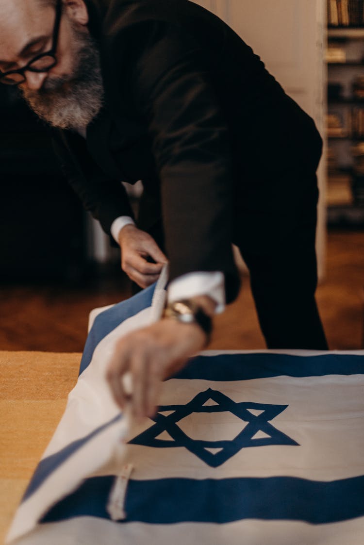 Bearded Man Folding The Flag Of Israel