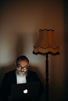 在东正教家庭的办公室里，一个男人在温暖的灯光下使用笔记本电脑
