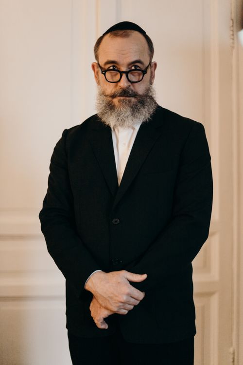 Free Orthodox Jewish man in a black suit and kippah, standing indoors, embodying traditional Judaic values. Stock Photo