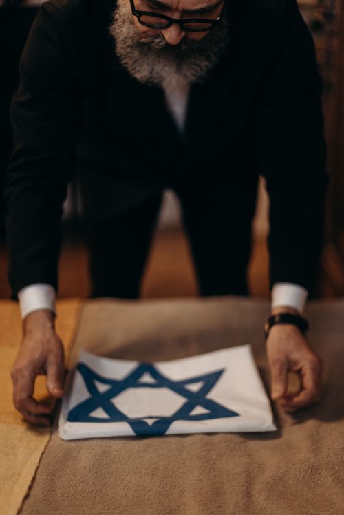 Free An orthodox Jewish man carefully folds an Israeli flag, symbolizing tradition and cultural heritage. Stock Photo