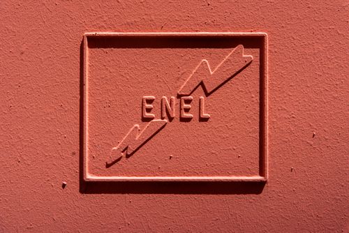 Free ENEL logo embossed on a textured red background, showcasing energy symbol. Stock Photo
