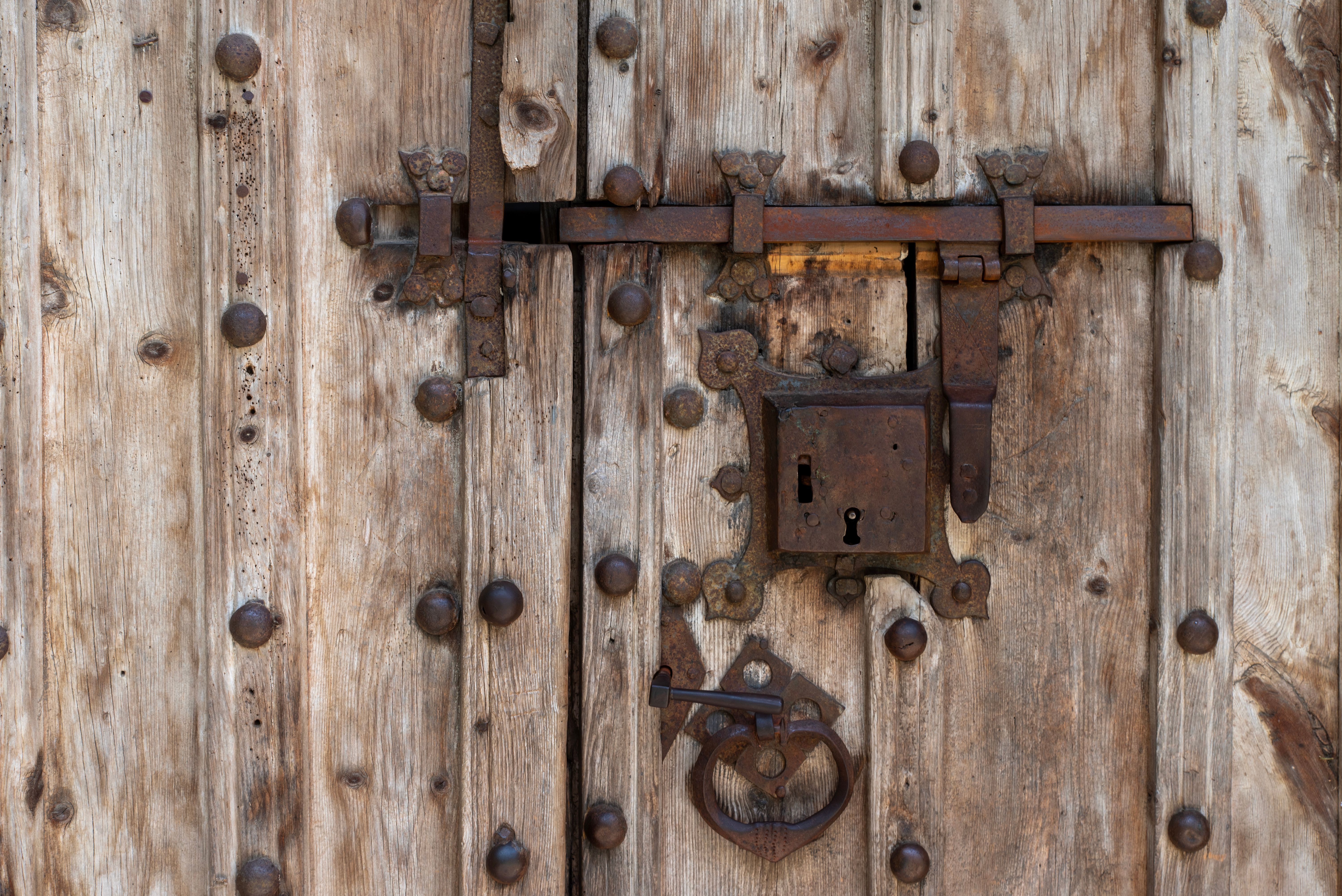 Fotomural Primer plano de una puerta rústica de madera con un sistema de cerradura y pestillo de hierro de estilo antiguo.