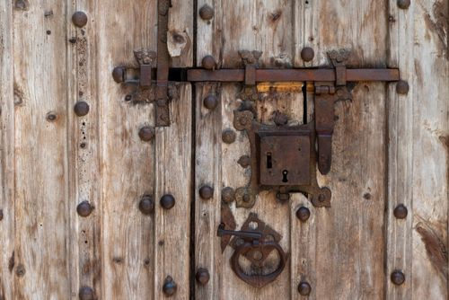 Free Close-up of a rustic wooden door featuring a vintage iron lock and latch system. Stock Photo