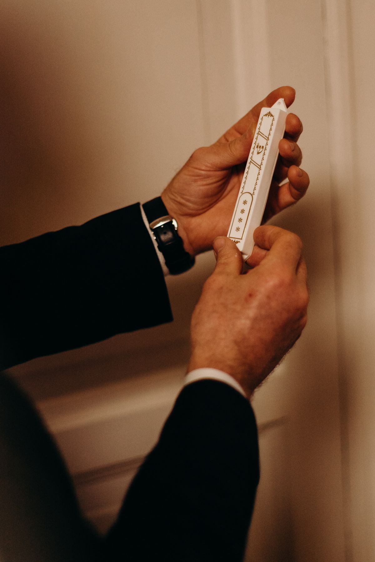 Hands affixing a mezuzah to a doorpost