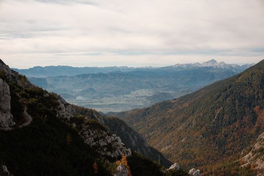Breathtaking mountain vista featuring a lush valley and distant peaks under a cloudy sky.