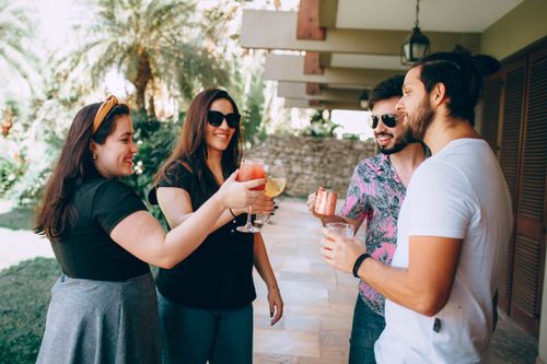 Free Group of friends enjoying drinks and conversation outdoors on a sunny day. Stock Photo
