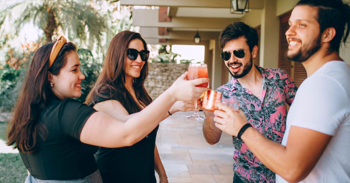 A cheerful group of friends enjoying drinks and conversation at an outdoor summer gathering