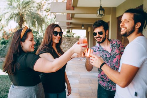Free A cheerful group of friends enjoying a summer party outdoors with drinks. Stock Photo