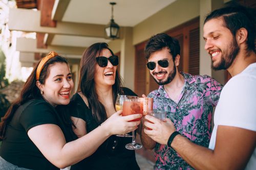 Free A joyful group of friends clinking glasses outdoors, captured in a warm and lively moment. Stock Photo