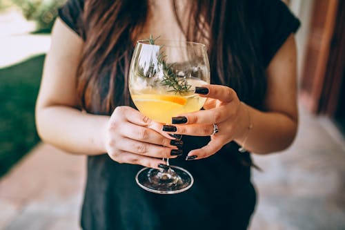 Woman in Black Dress Holding A Cocktail Drink