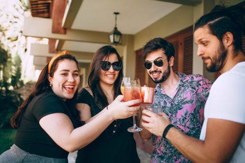 Free Happy group of friends enjoying a toast with drinks outdoors on a sunny day. Stock Photo