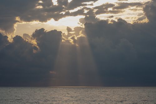 Free Sunlight breaks through storm clouds over the Black Sea in Batumi, Georgia, creating a dramatic coastal seascape. Stock Photo