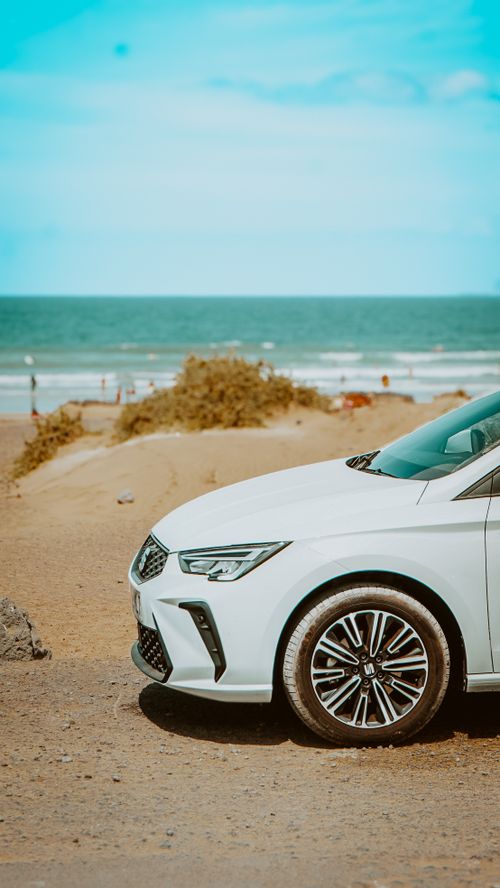 Free A sleek white car parked by the ocean on a sunny day in Lanzarote, Spain. Stock Photo