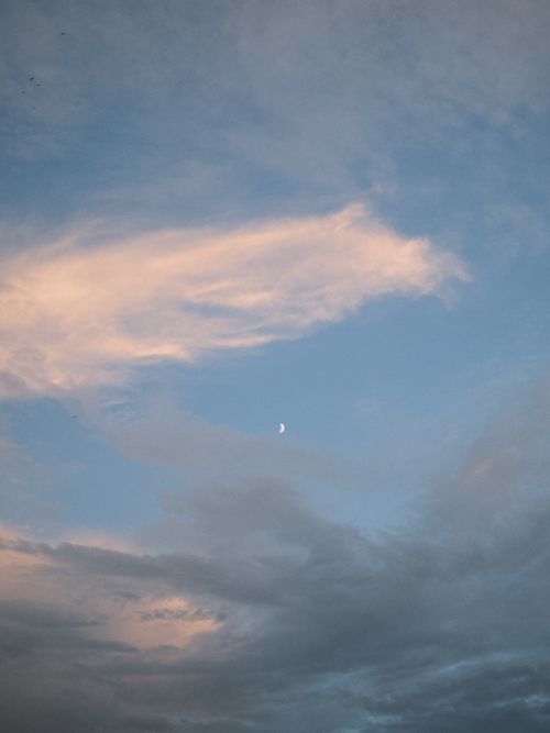 Free Beautiful evening sky with soft clouds and a visible crescent moon, creating a calming atmosphere. Stock Photo