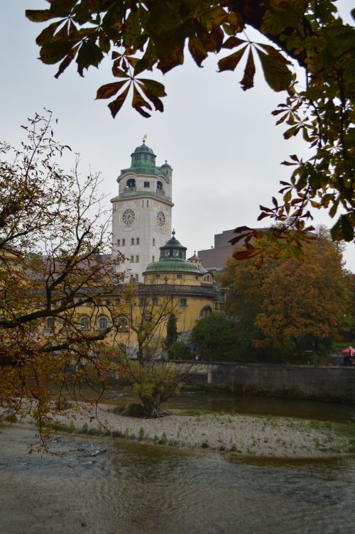Free Scenic view of a historic European tower surrounded by autumn trees and a river. Stock Photo