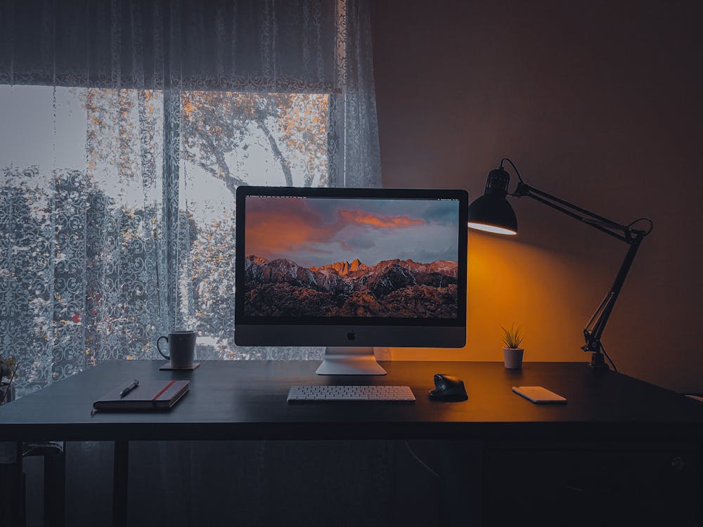 Computer with mountains on screen in dark room · Free Stock Photo