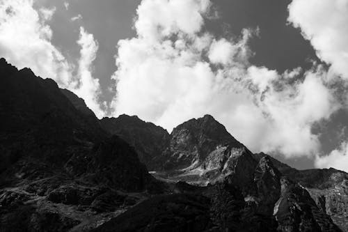 Grayscale Photo of Rocky Mountain Under Cloudy Sky