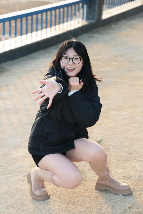 Free A cheerful young woman in boots and a coat reaching out with a friendly gesture outdoors. Stock Photo