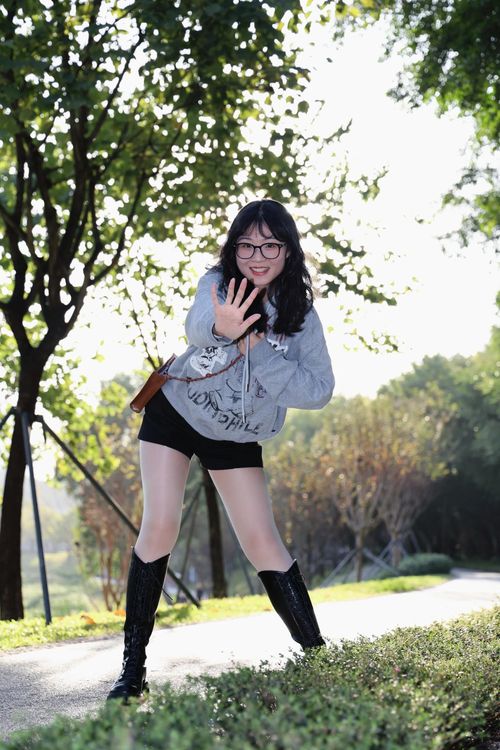 Free A cheerful woman posing on a sunny day in a park in Hefei, China, showcasing a trendy casual outfit. Stock Photo