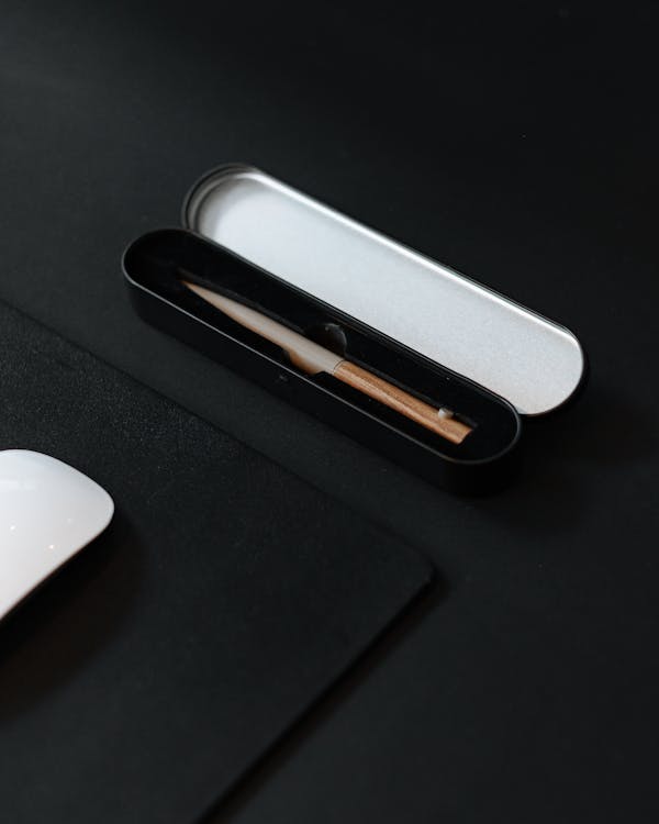 Sleek black pen case with a silver lid, containing a stylish bamboo pen, perfect for modern professionals.