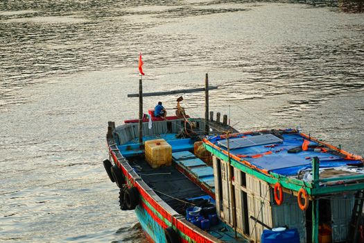 Traditional fishing boat on serene water in Da Nang, Vietnam at sunset.