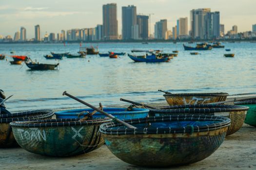 Round fishing boats on the Da Nang beachfront with cityscape background.
