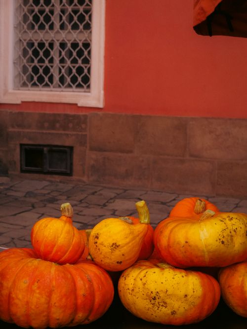 Free Vibrant pumpkins stacked against a distinctive Czech urban backdrop. Stock Photo