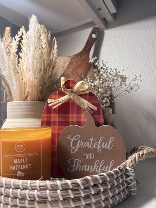 Free Warm autumn-themed arrangement featuring a scented candle, basket, and dried plants for a cozy vibe. Stock Photo