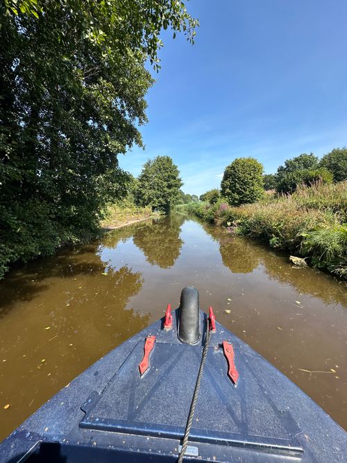 Free Peaceful boat ride through lush canal scenery under a vibrant blue sky. Stock Photo