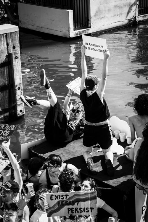 Free Protesters demonstrate on a canal boat in Amsterdam, highlighting LGBTQ+ rights with signs in a black and white capture. Stock Photo