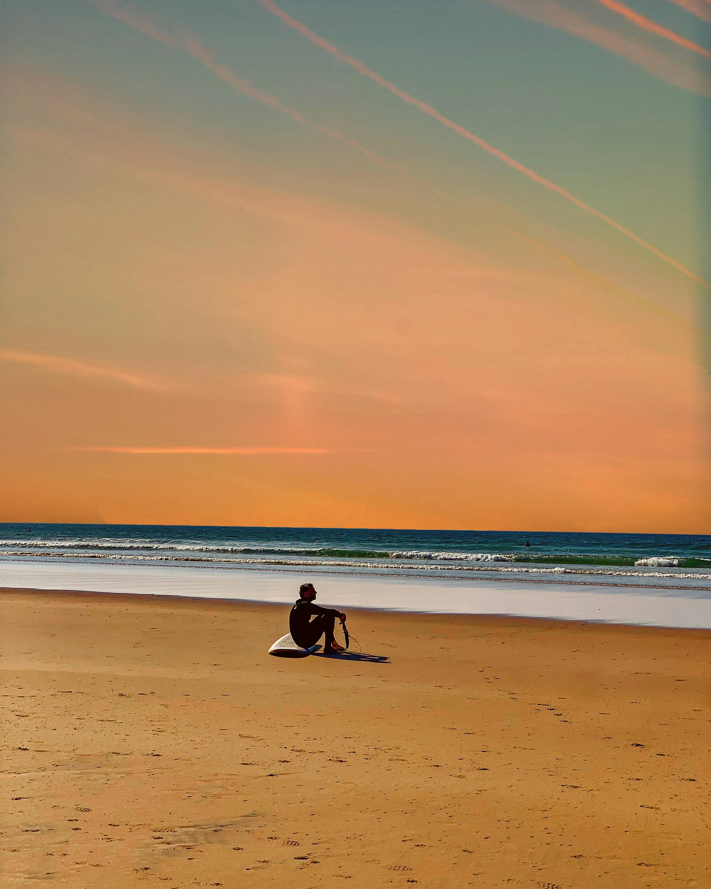 A Man Sitting on the Seawall at Night · Free Stock Photo