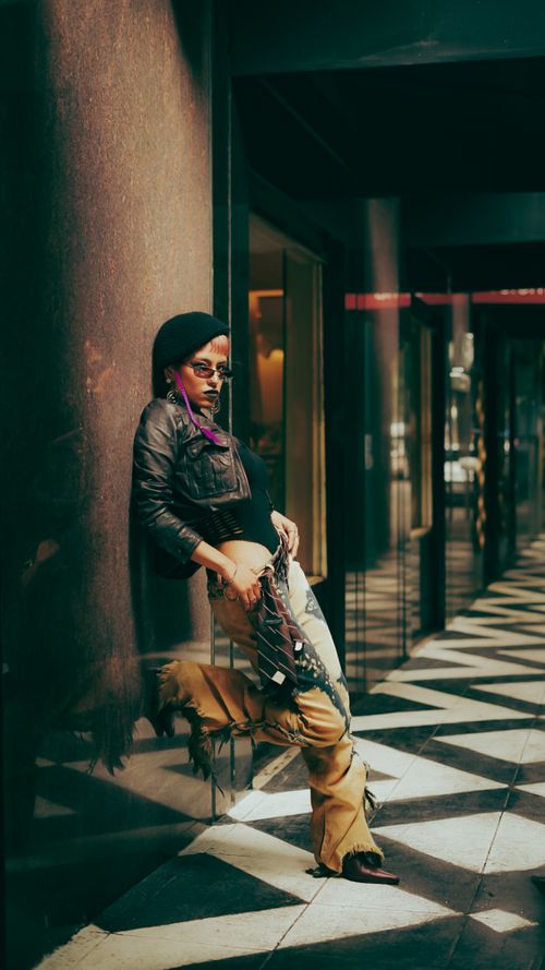 Free Stylish person with unique attire striking a pose in a modern urban setting. Stock Photo