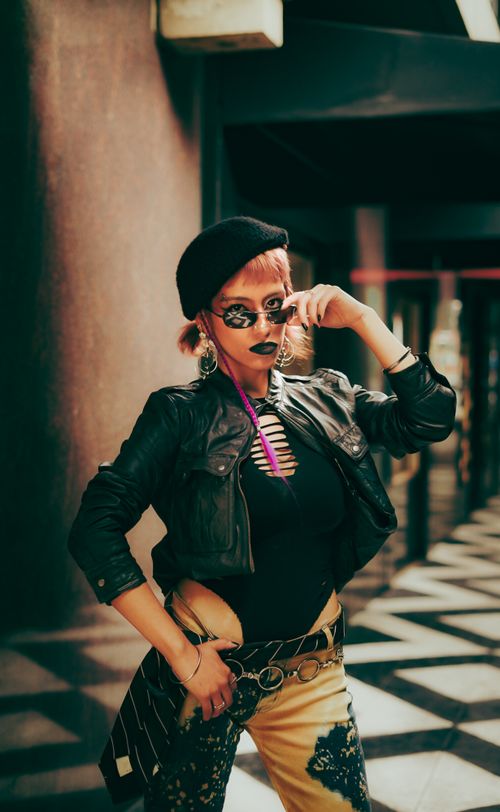 Free Fashionable woman posing confidently in a chic urban setting with bold makeup and trendy attire. Stock Photo