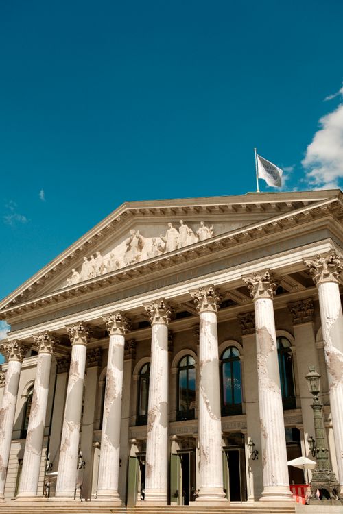 Free The historic facade of Munich's National Theater against a vibrant blue sky. Stock Photo