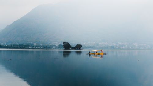 Free A peaceful scene of a shikara boat gliding on the tranquil waters of Dal Lake, Srinagar. Stock Photo