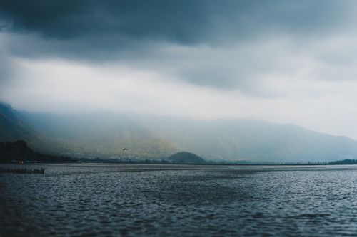 Free A tranquil scene of Dal Lake with mountains and cloudy skies in Srinagar, Kashmir. Stock Photo
