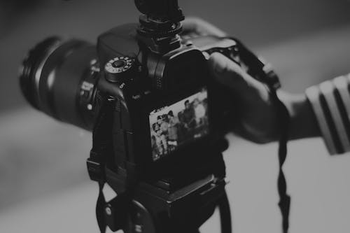 Fotografi Grayscale Orang Yang Memegang Kamera Dslr Hitam