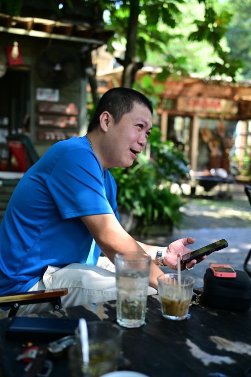 Free Man relaxing in outdoor cafe setting, checking phone, enjoying drinks. Stock Photo