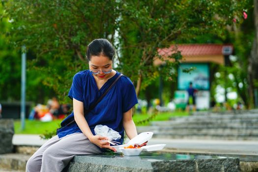 A young woman savoring street food outdoors in Hue, Vietnam, exemplifying local culinary culture.