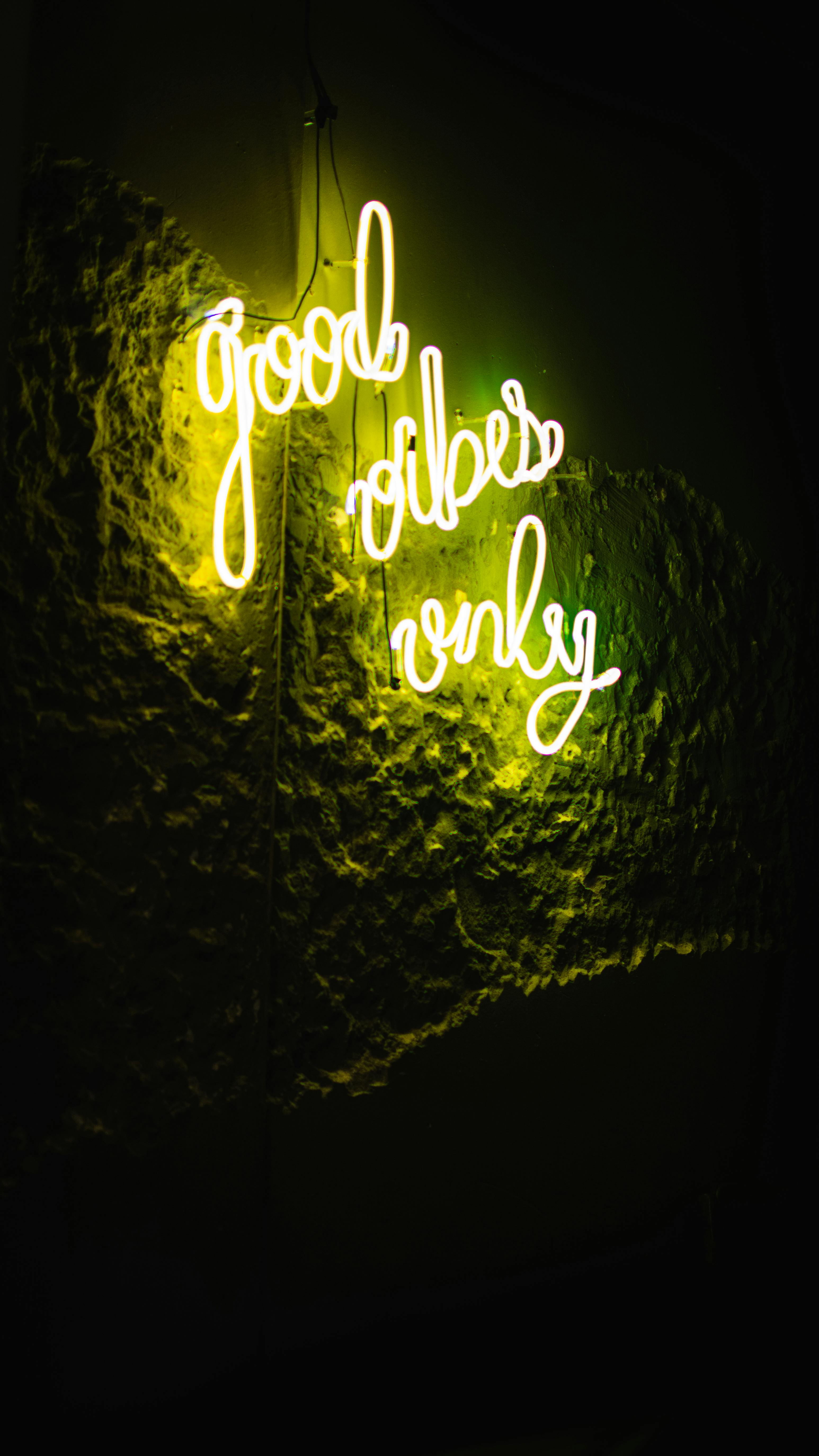 A glowing neon sign displaying 'Good Vibes Only' on a textured wall, symbolizing positivity.